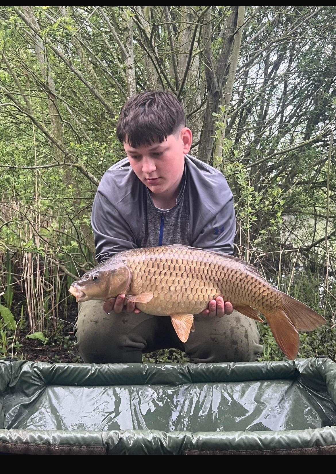 Young angler holding a recent common carp catch at Alderwood Fishery