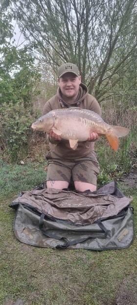 Angler with a carp caught at dusk at Alderwood Fishery