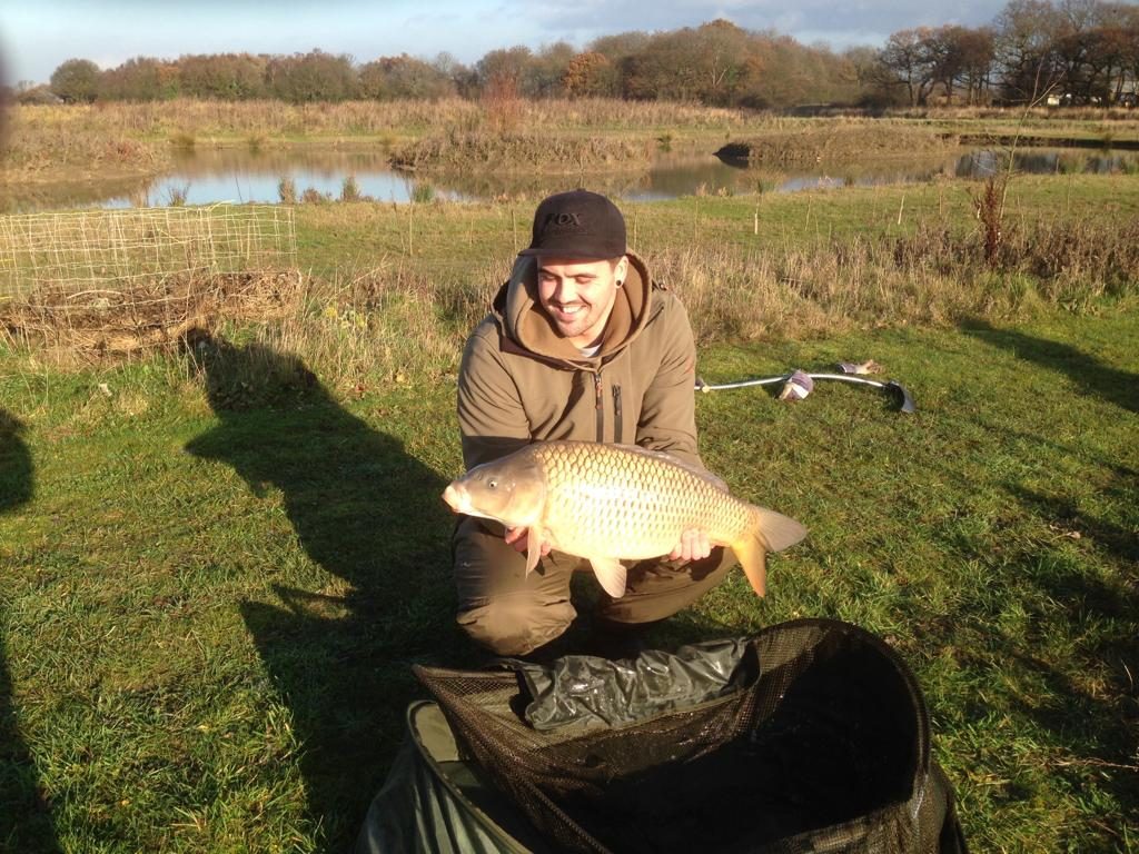 Angler holding a carp on the bank at Alderwood Fishery