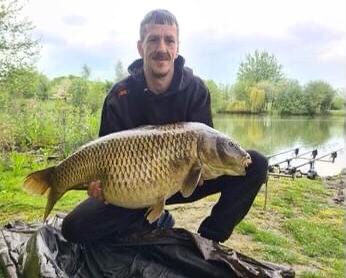 Angler holding a broad common carp on the bank at Alderwood Fishery